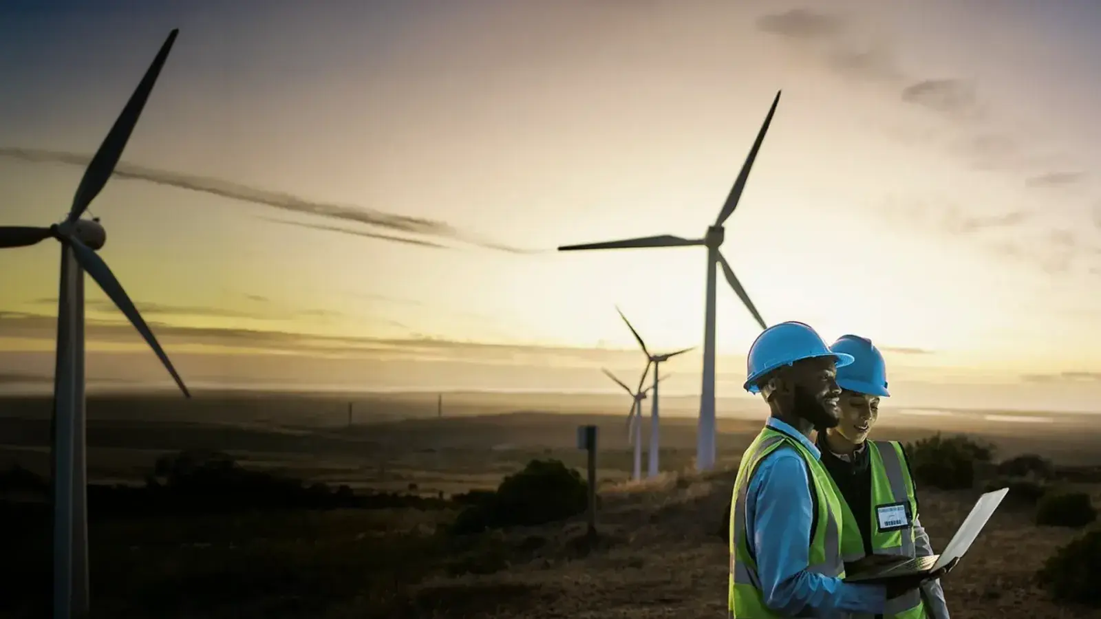 Two environmental workers in a field with wind turbines
两名环保工作人员在风力发电机组附近的田野中开展工作